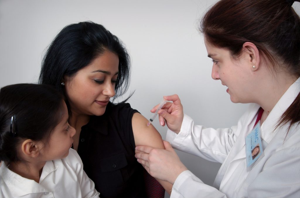 A Health Care provider gives a young woman a shot